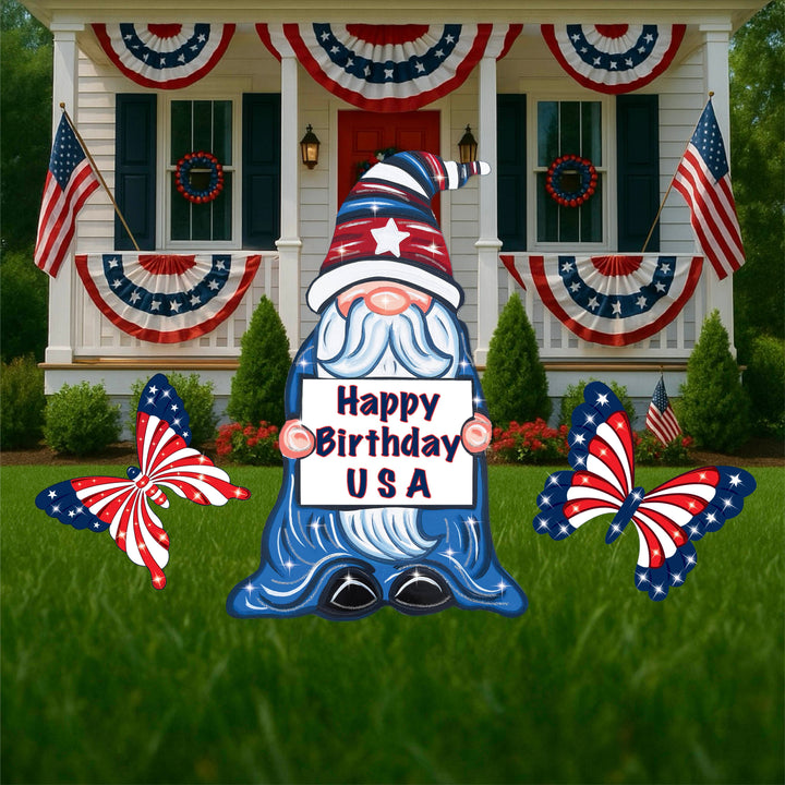 Festive garden gnome outdoor yard decoration. Gnome is dressed in red, white and blue and is holding a sign that reads, "Happy Birhday USA" - holiday lawn signs for 4th of July. 