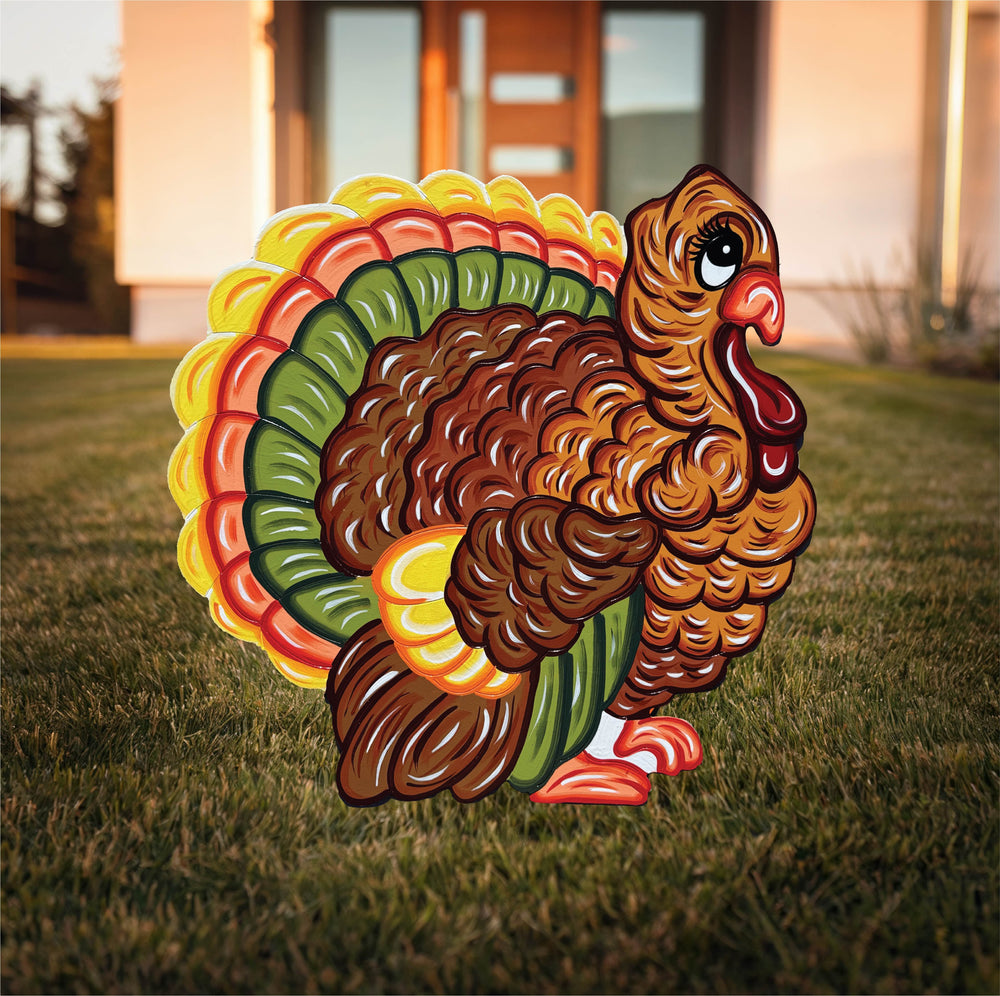 A colorful yard sign depicting a turkey with a vibrant tail displayed on a lawn.