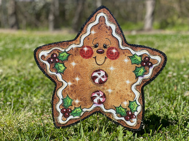 Christmas themed gingerbread star outdoor yard sign. Star features a smiley face with white "frosting" around the edges and peppermint circles for buttons. Cute Christmas yard signs with stakes are perfect for the Holiday Decorating enthusiast in your home. 