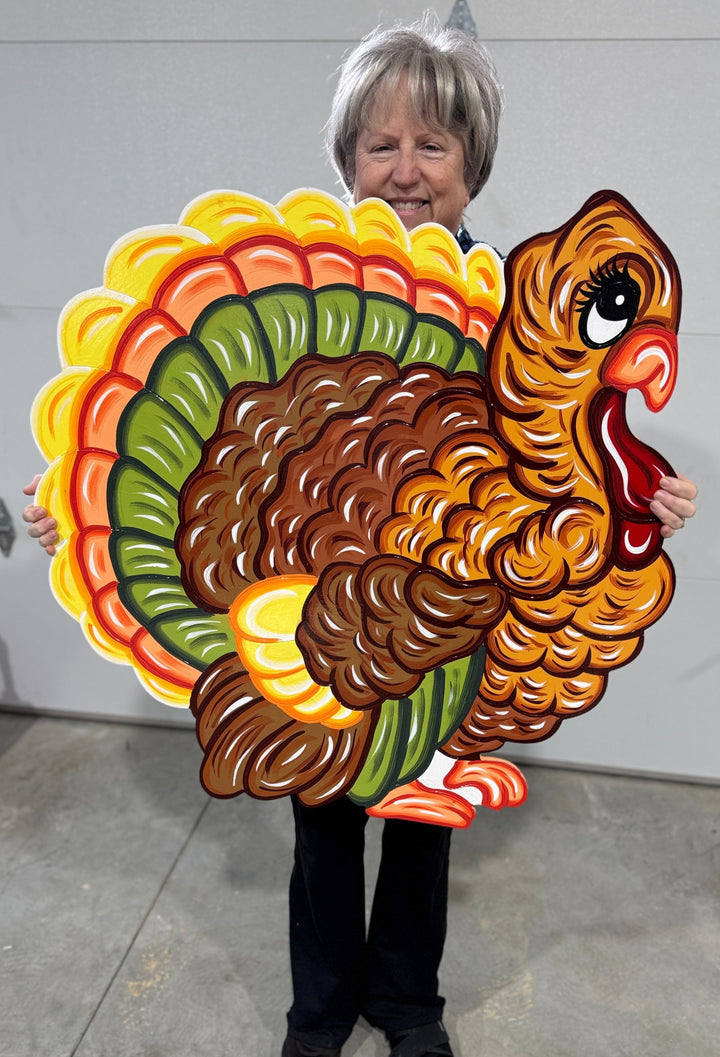 Mary, the owner of Yard Art Decor and More holding her outdoor decorative Turkey Yard Sign for fall decorating.  