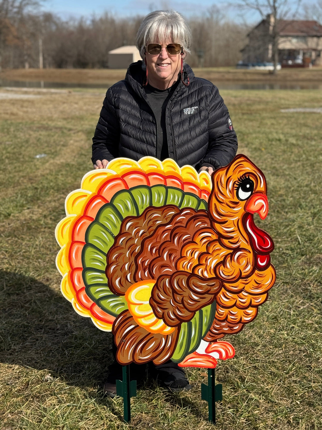 Person holding a large, colorful turkey decorative sign outdoors.