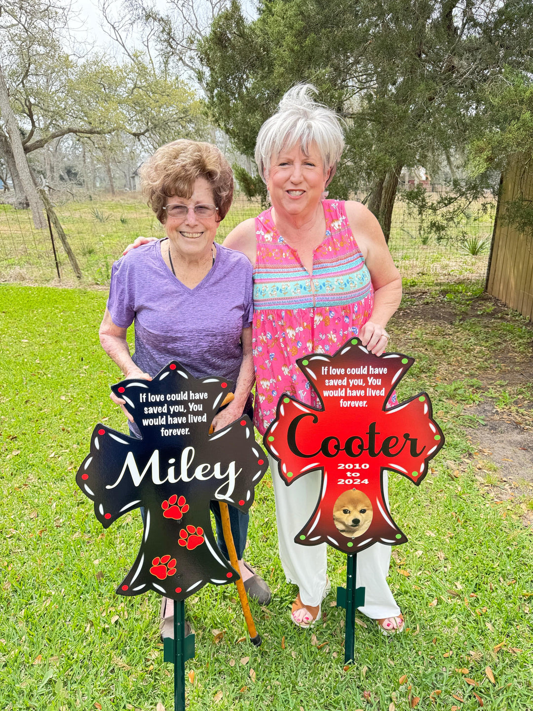 Set of 2 pet memorial customizable crosses for lawns, gardens, porches and walkways. One personalized pet cross in black with white letters and the name Miley on it, the other outdoor pet yard memorial cross in red with black and white lettering that says Cooler. Add a custom quote to honor your beloved pet. 