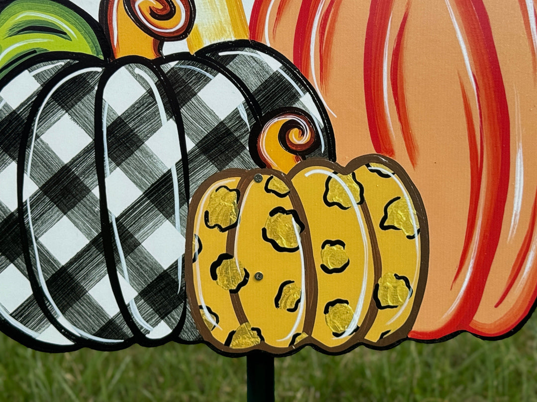 close up view of leopard print pumpkin on Welcome Fall Sign on top of three Fall pumpkins yard art decoration: one pumpkin is black and white plaid, one pumpkin is leopard print, and one pumpkin is orange
