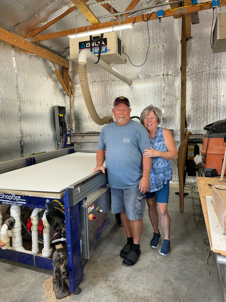 Bruce and Mary Amick standing beside a computerized numerical cutting machine that cuts our yard art signs