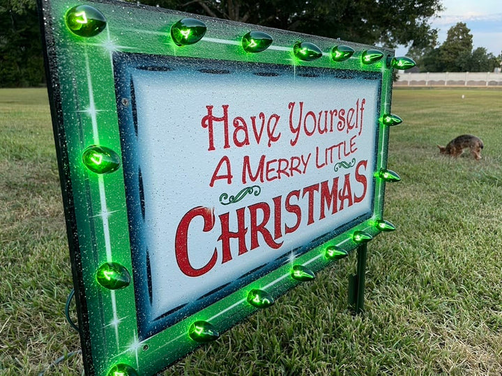 Daytime angled view of a handcrafted wooden holiday yard display showing the glitter clear-coat texture, green border accent, and durable ground installation stakes.