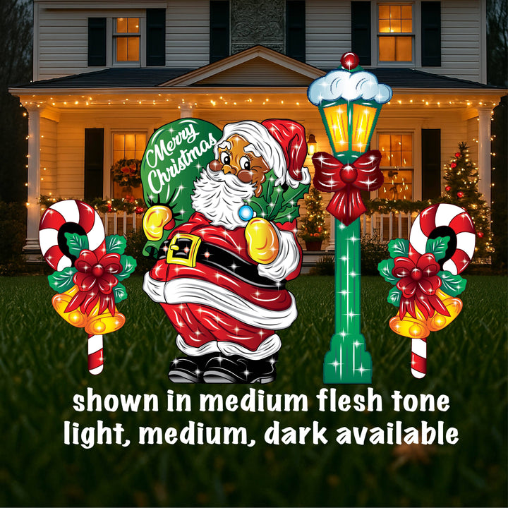 A yard sign featuring a smiling Santa Claus holding a mistletoe and a green bag, accompanied by a 'Santa Stop Here' sign, a lamp post, and presents placed on the grass in front of a house with Christmas decorations.