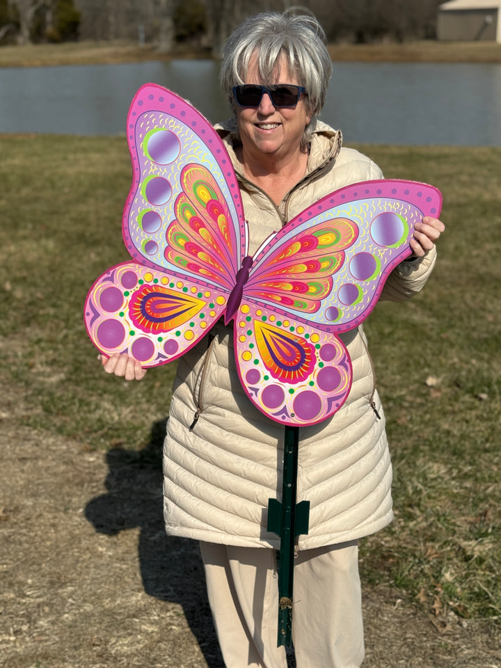 Owner holding large pink butterfly yard sign with vibrant colors and circular patterns – spring outdoor lawn decor shown for size reference.