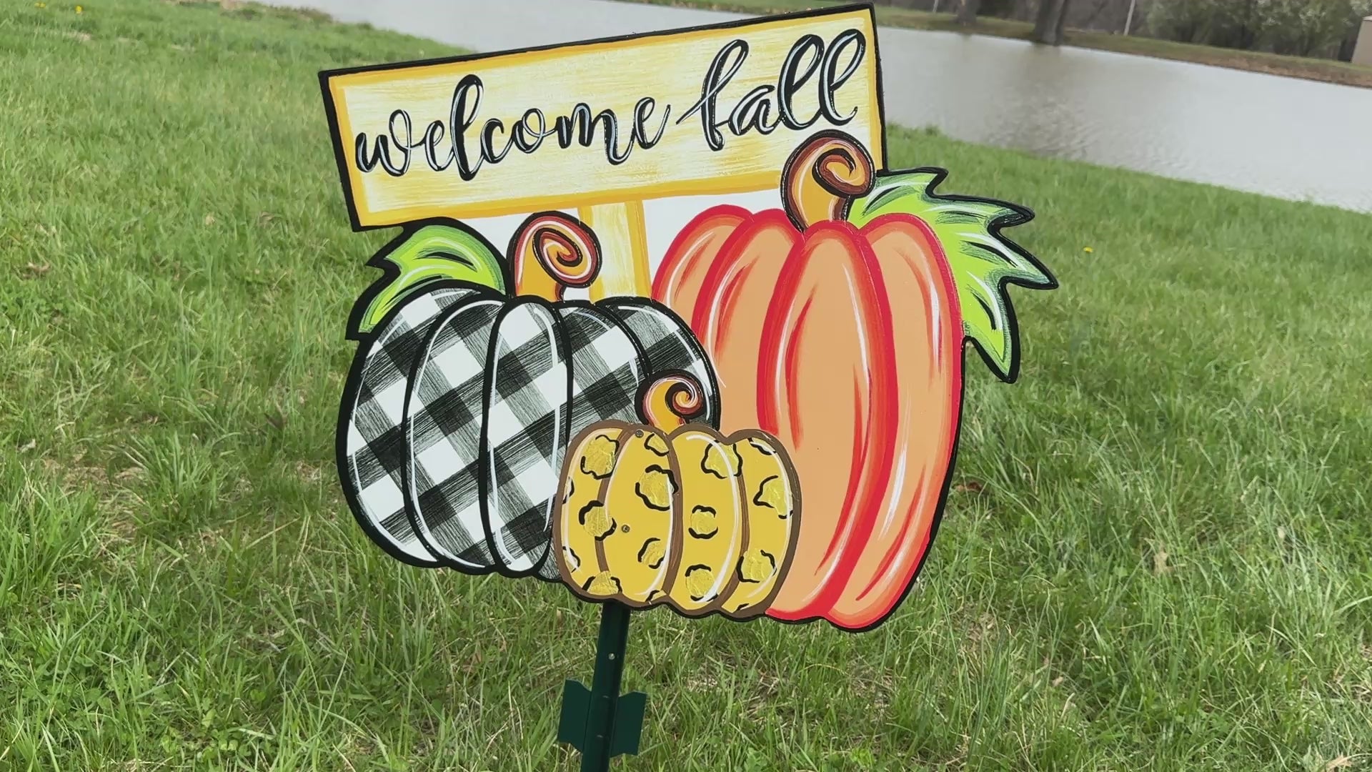 video of Welcome Fall Sign on top of three Fall pumpkins yard art decoration: one pumpkin is black and white plaid, one pumpkin is leopard print, and one pumpkin is orange