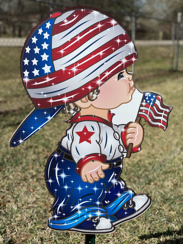 patriotic yard art decorative lawn sign with stake. Child with a red, white and blue baseball cap on holding an american flag. 